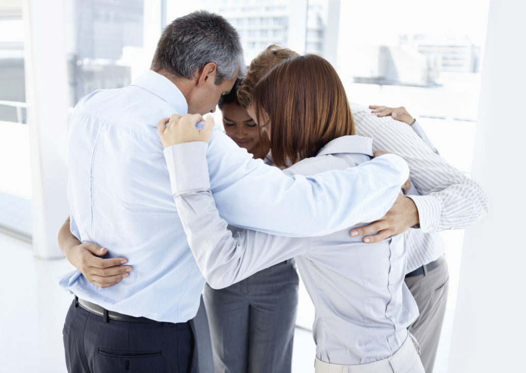 A group of people hugging in the middle of a room.