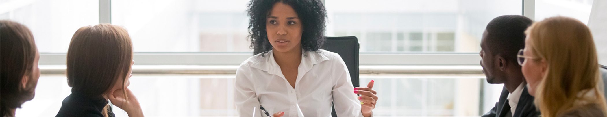 coaching-development-banner2100x405 A woman sitting at a table in front of a glass.