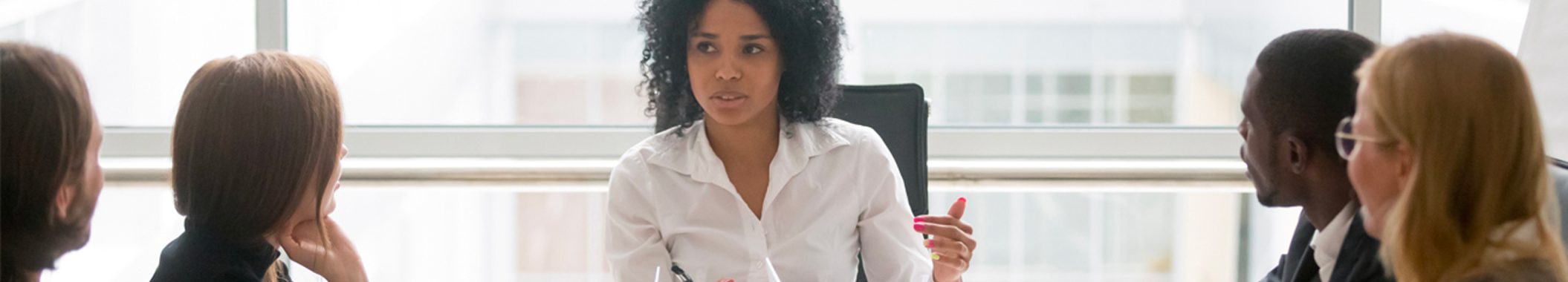coaching-development-banner2100x405 A woman sitting at a table in front of a glass.